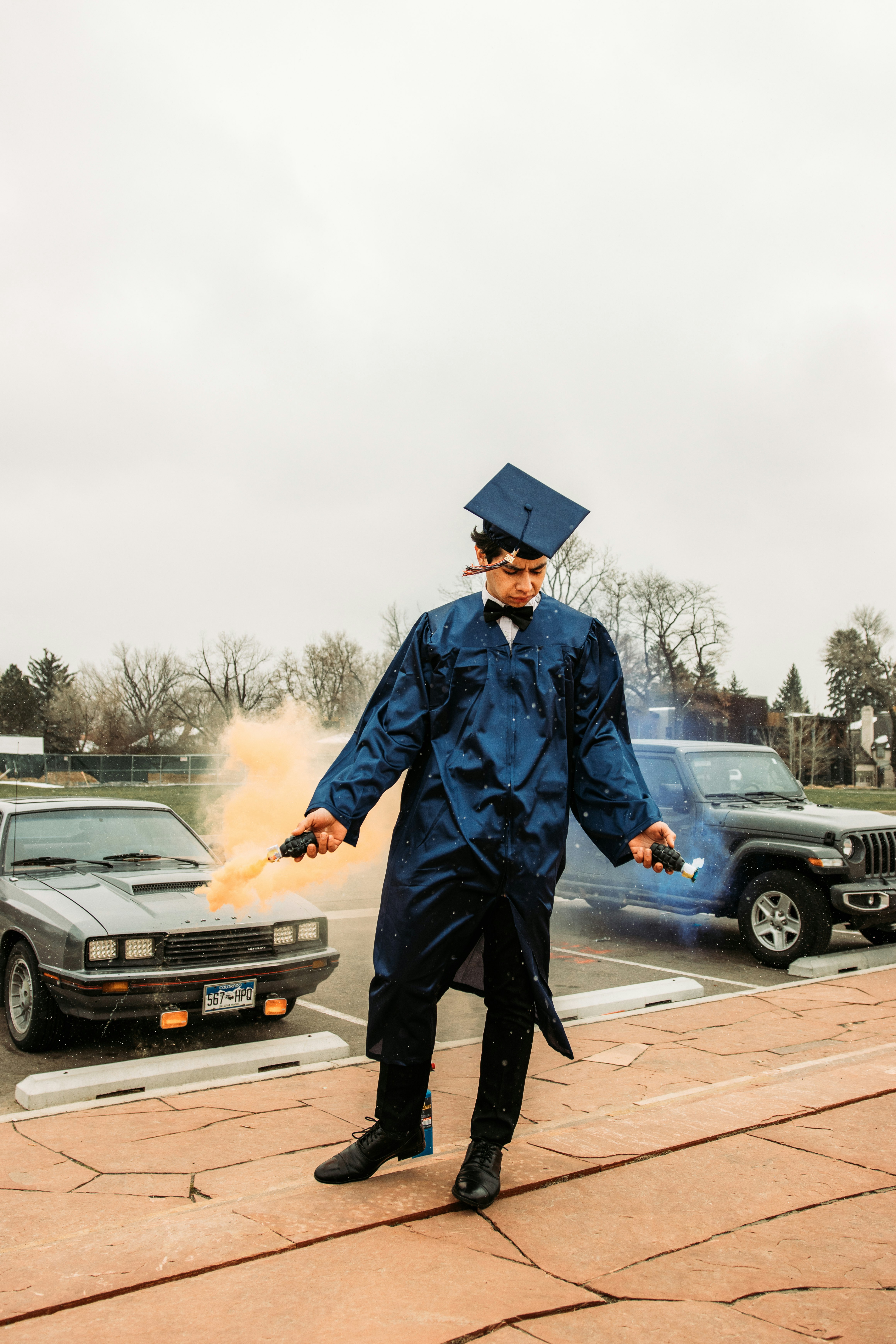 man in blue academic dress and black mortar board standing on road during daytime